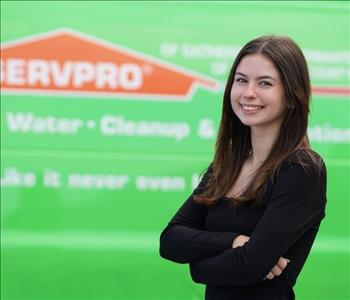 female employee with long brown hair standing next to a SERVPRO truck