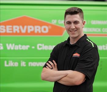 male employee wearing a black SERVPRO shirt and standing next to a SERVPRO truck