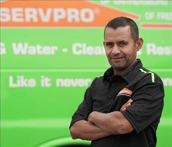 male employee wearing a black SERVPRO shirt standing next to a SERVPRO ruck