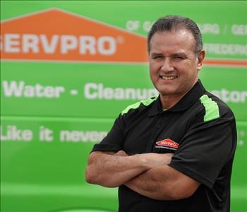 male employee with brown hair wearing a black SERVPRO shirt standing next to a SERVPRO truck