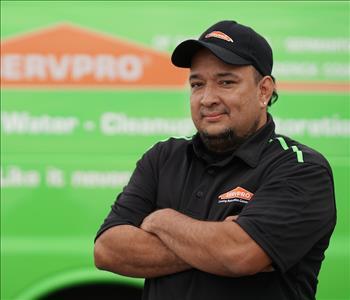Man in late 30s with shorter dark hair and chin beard, wearing a SERVPRO T-shirt, standing next to a SERVPRO truck 