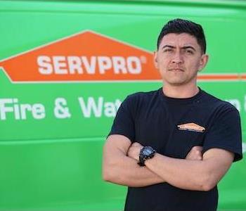 Younger, clean-shaven man, wearing a SERVPRO T-shirt and a serious expression, standing next to a SERVPRO truck