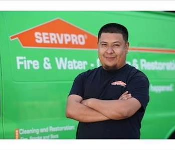 Man in mid-thirties with short, neatly trimmed, dark hair and chin beard in SERVPRO T-shirt, standing next to a SERVPRO truck