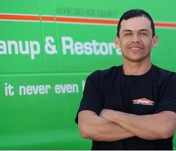 Middle-aged male with short dark hair wearing a SERVPRO T-shirt and a confident smile by a SERVPRO truck