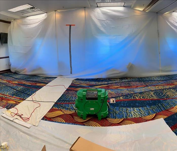 containment barrier enclosing portion of large conference room with an air scrubber in the foreground